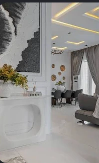 White interior with abstract artwork, flowers and a view into a living and dining space