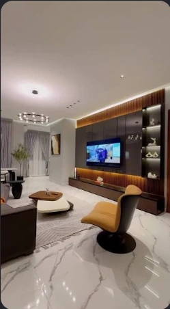 Living room with a timber media wall, marble-effect floor and mustard accent chair