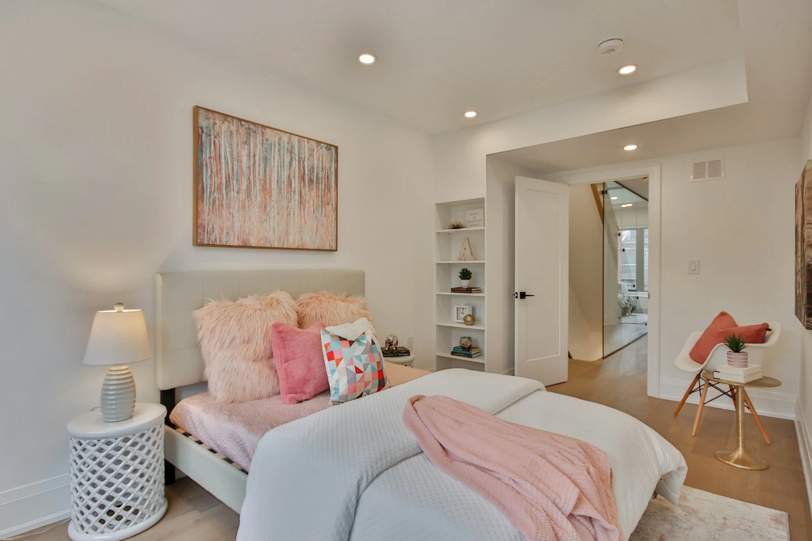 A white bedroom with pastel pink textiles and soft decorative details