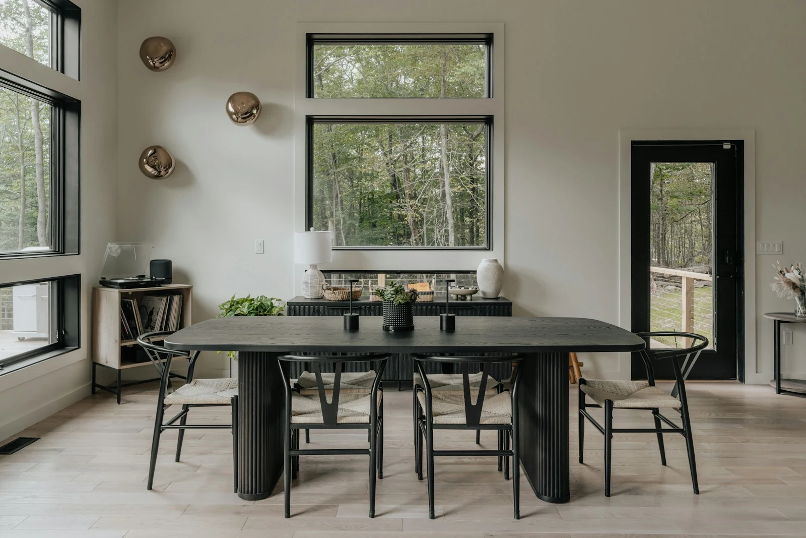 A dining room with a dark table, chairs and large windows