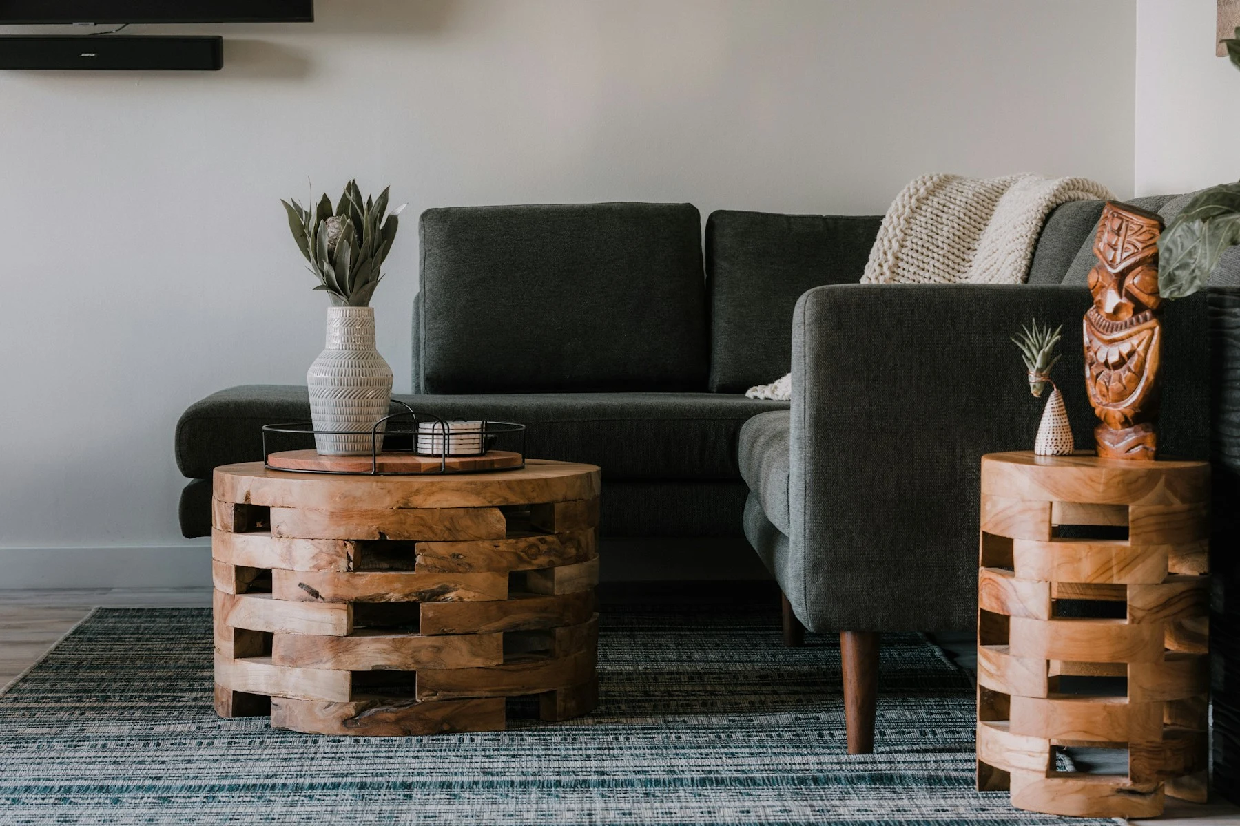 A modern sitting area with dark upholstered seating and sculptural timber tables