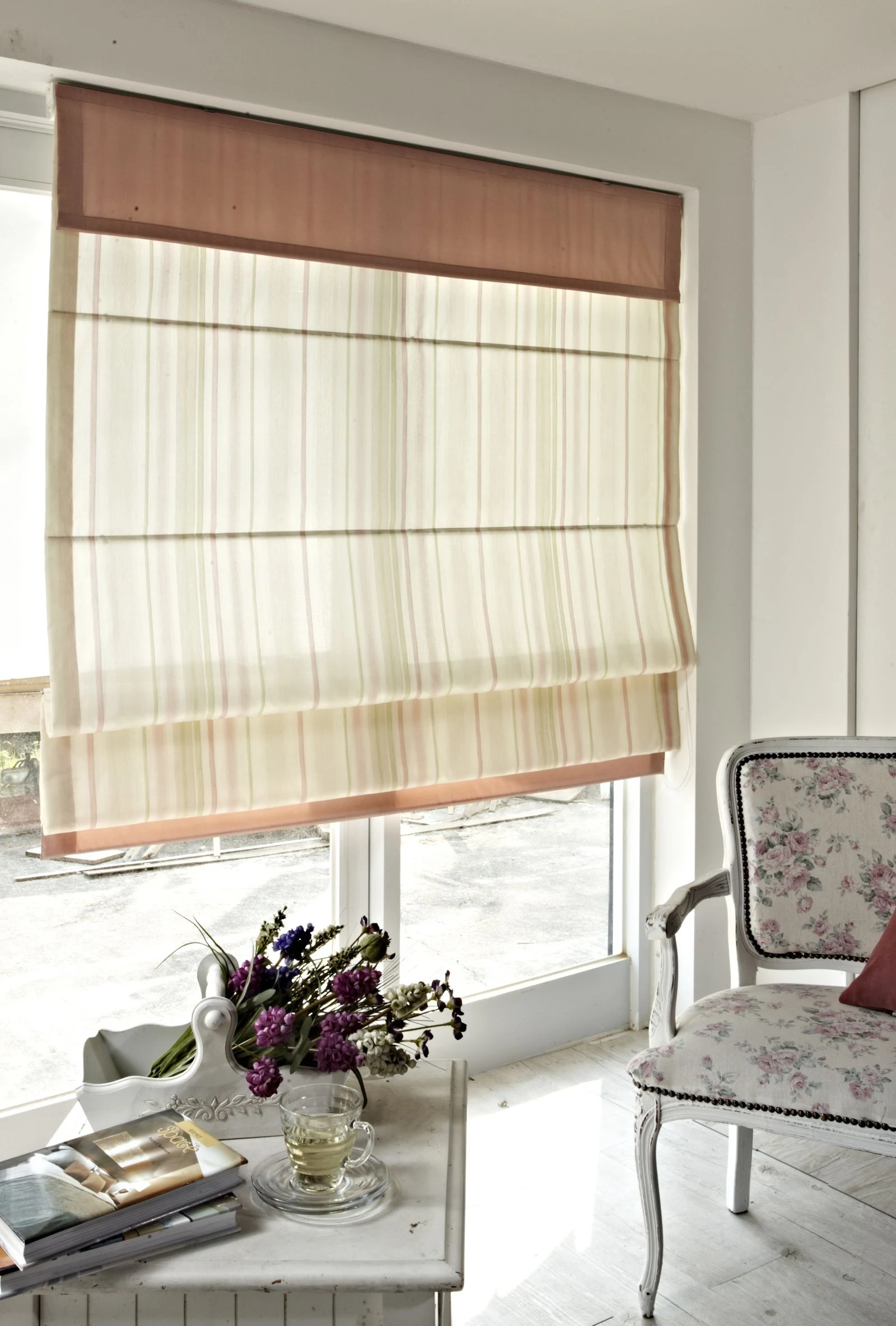 A white interior corner with purple flowers and a patterned chair