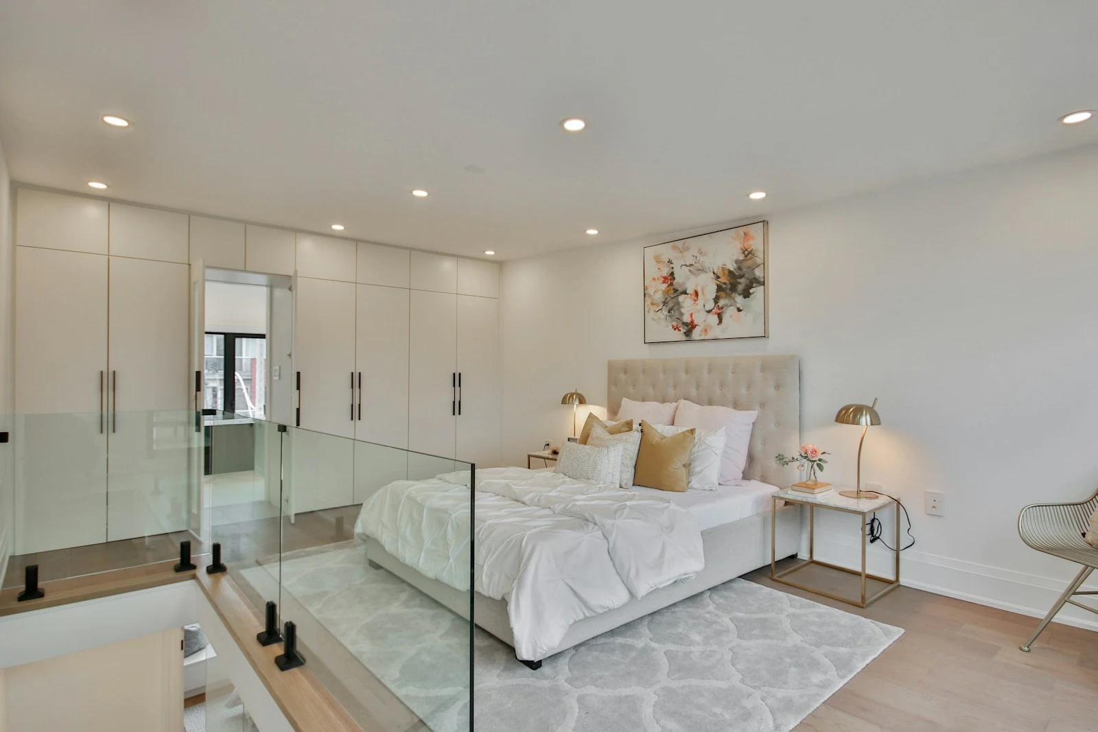 A bright primary bedroom with white textiles and glass detailing